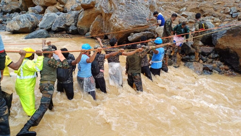 a group of people crossing a river Indian army rescuing  landslide in WAYANAD